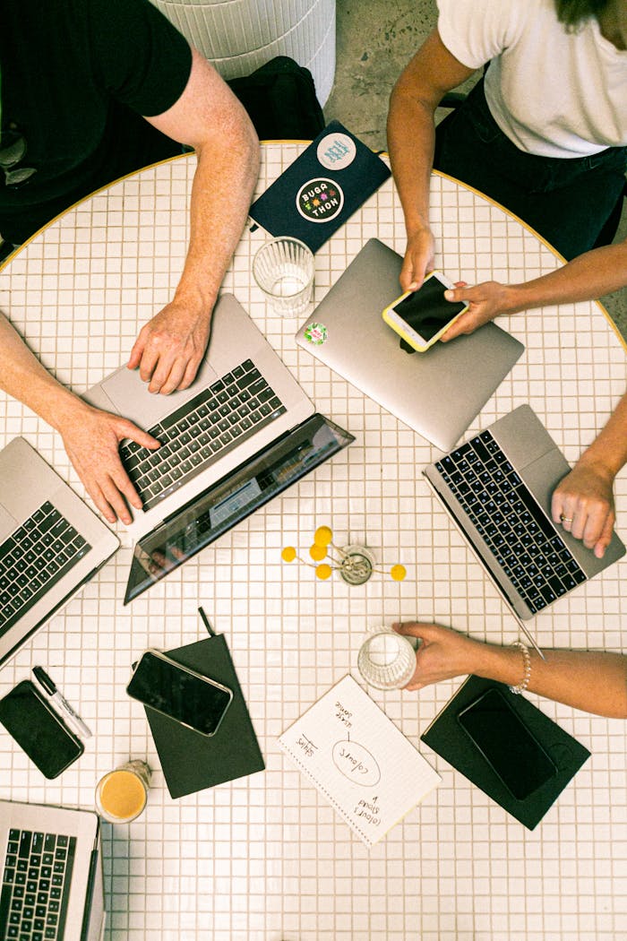 about-01 Top view of a team collaborating with laptops, phones, and notes in a modern office.